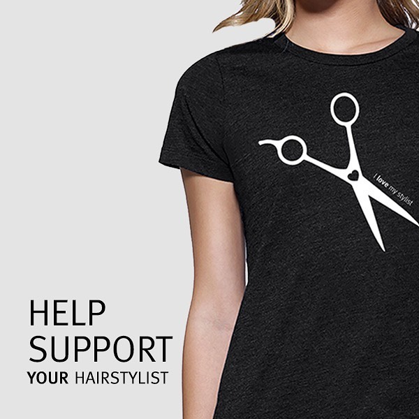 A woman wearing a black t-shirt featuring a white scissor design with the text "Help support your hairstylist at Breeze Salon.